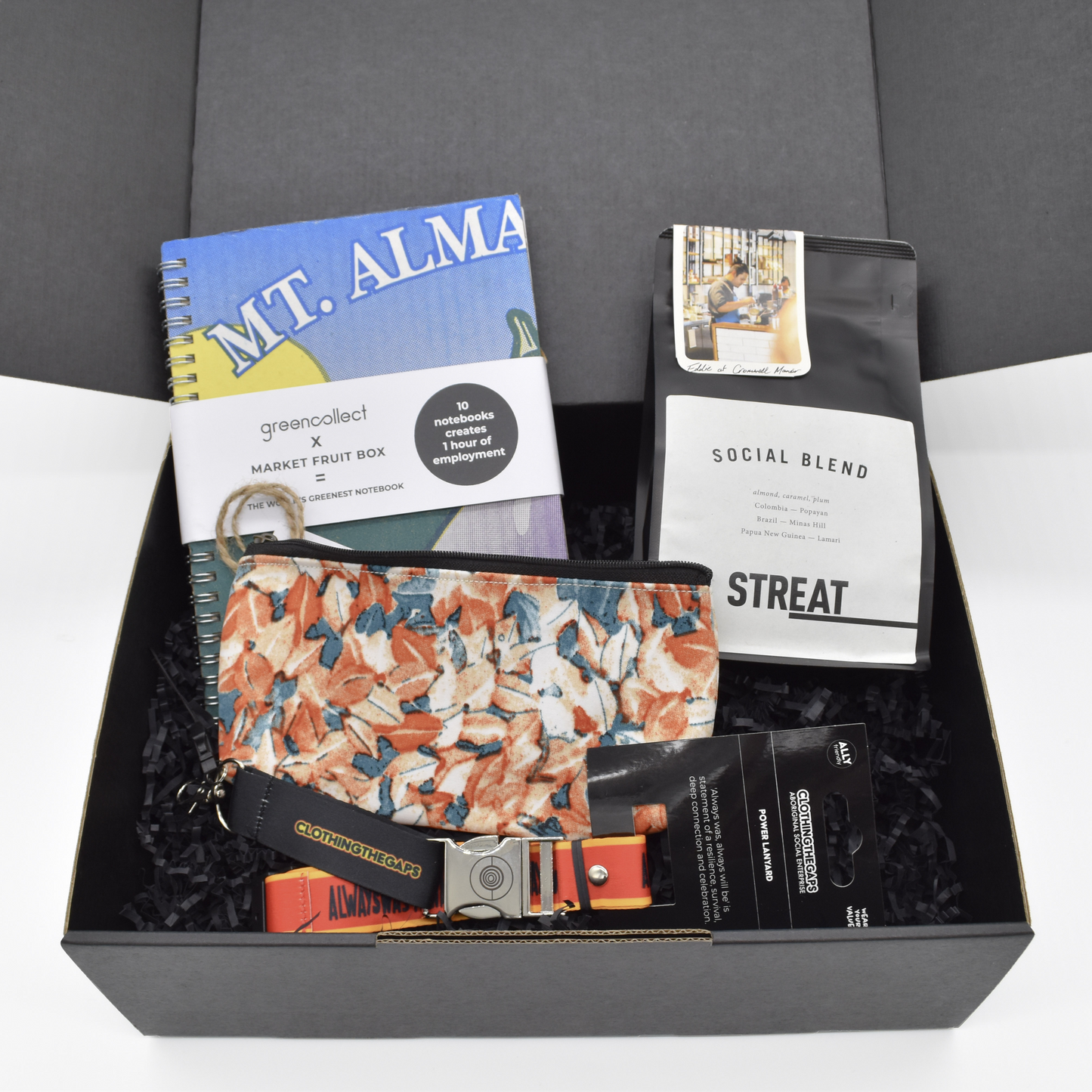 Gift box with a pouch, bag of coffee, note book and keychain lanyard on a white background.
